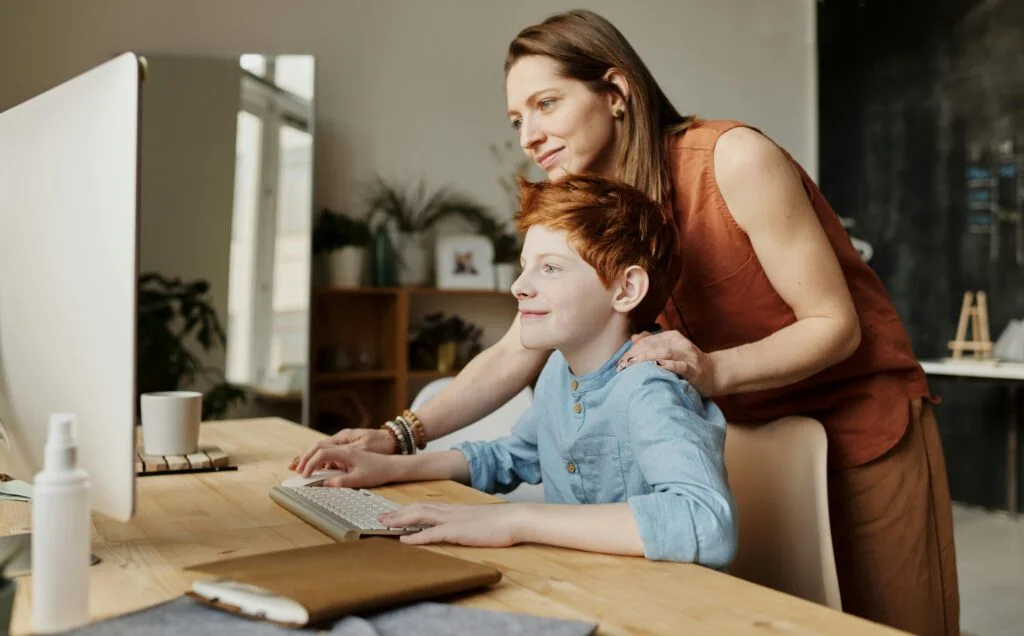 mother helping son on computer for virtual counseling