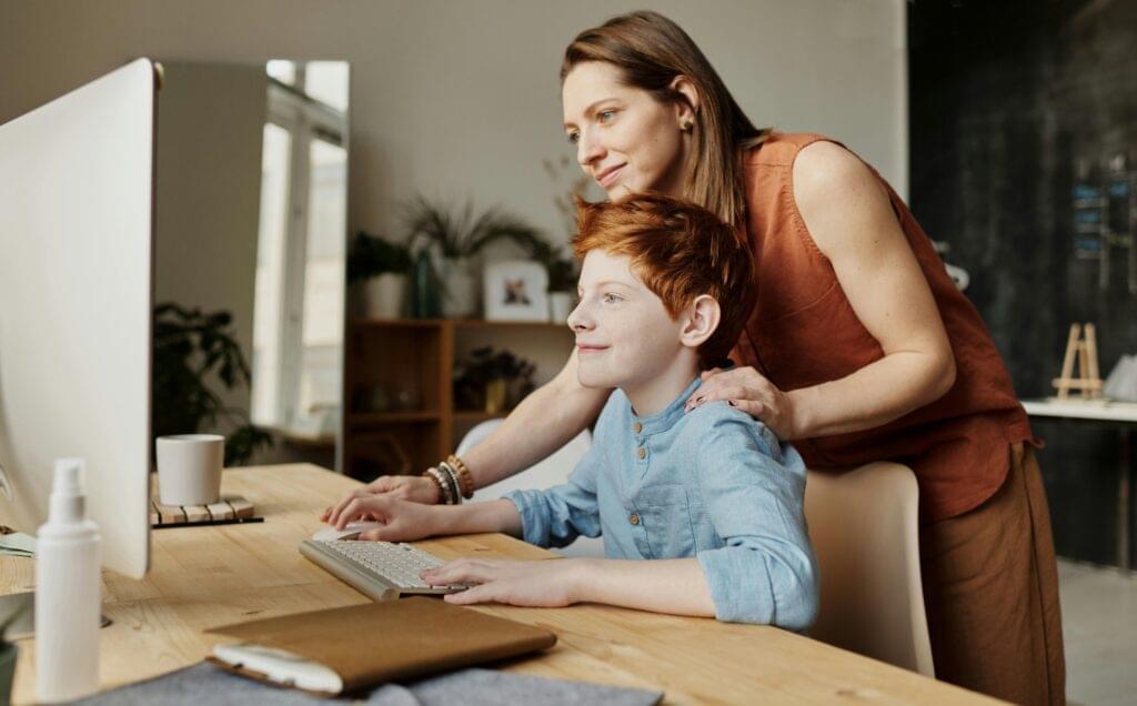 mother helping son on computer for virtual counseling